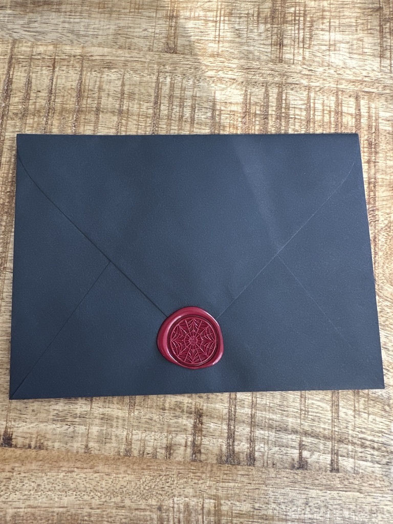 A dark envelope closed with a red spiderweb wax seal.