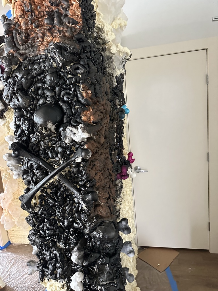 Skulls, crossed bones, and textured surfaces take shape on a column.