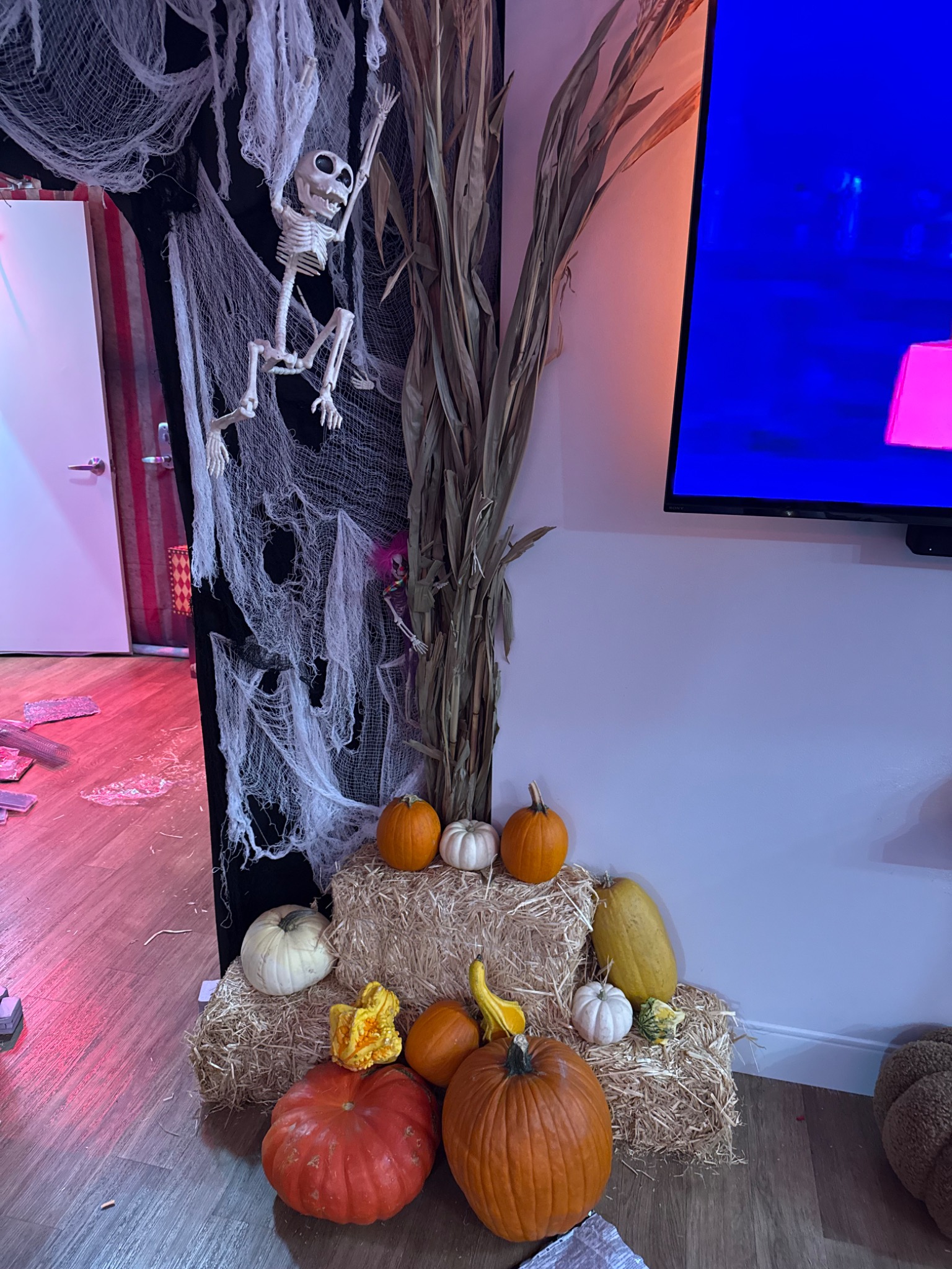 Pumpkins, straw, branches, and cobwebs dress the edge of the room.