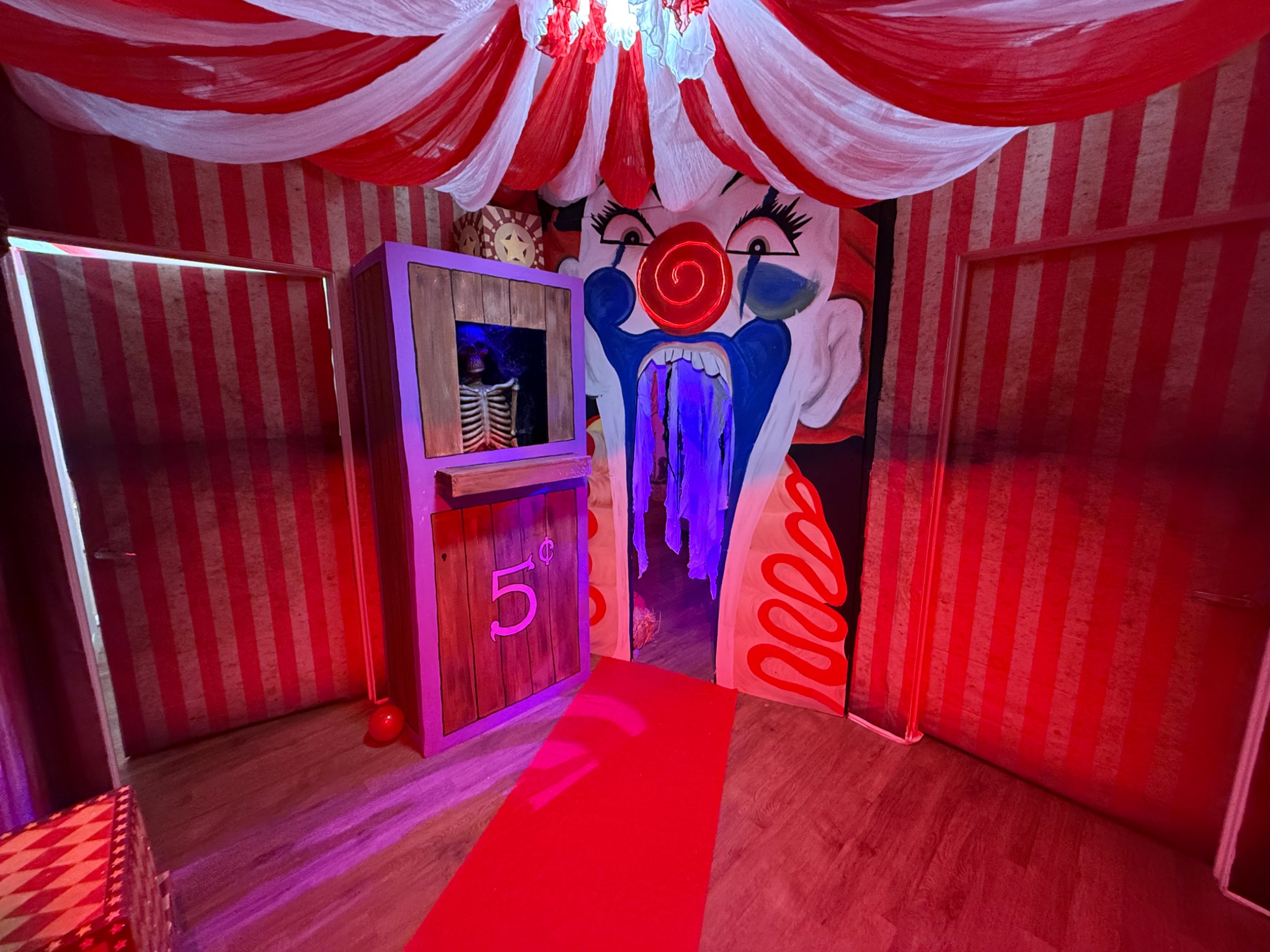 The finished Freak Show entrance, with an oversized clown-mouth doorway, a fortune-teller booth, and a red-and-white fabric canopy.