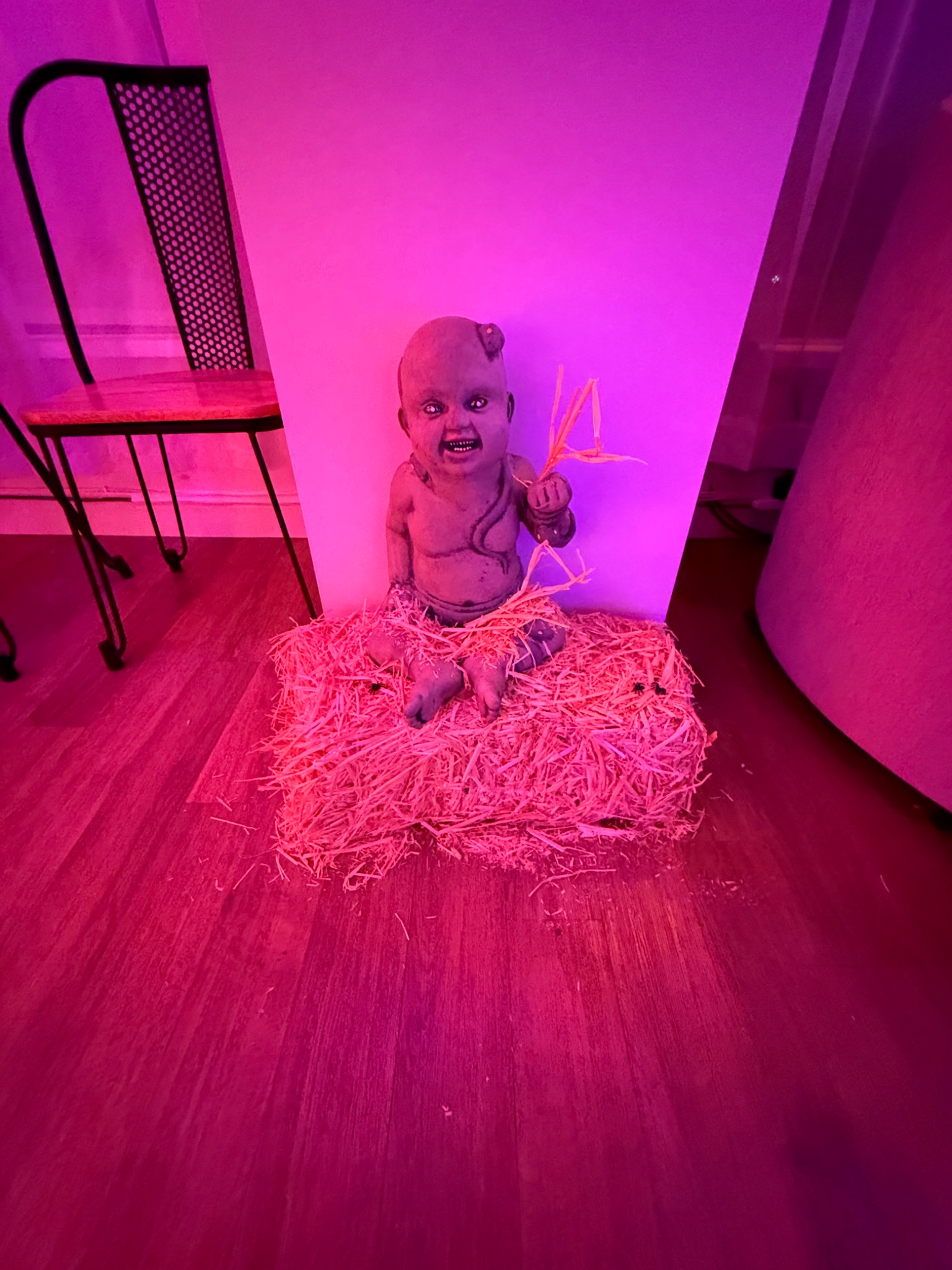 A small doll tucked into a bed of straw.