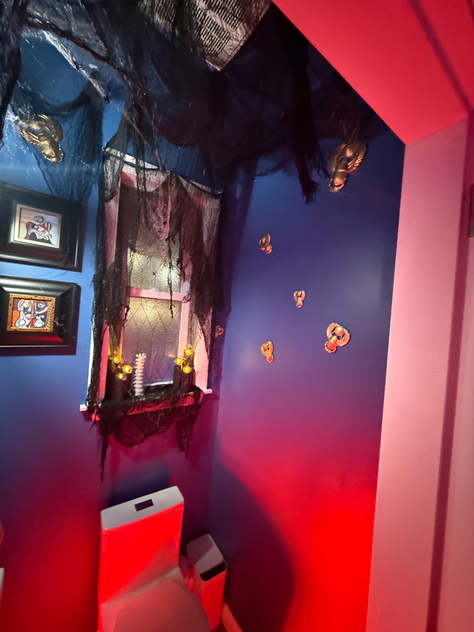 Candlelight and red illumination around the bathroom window.