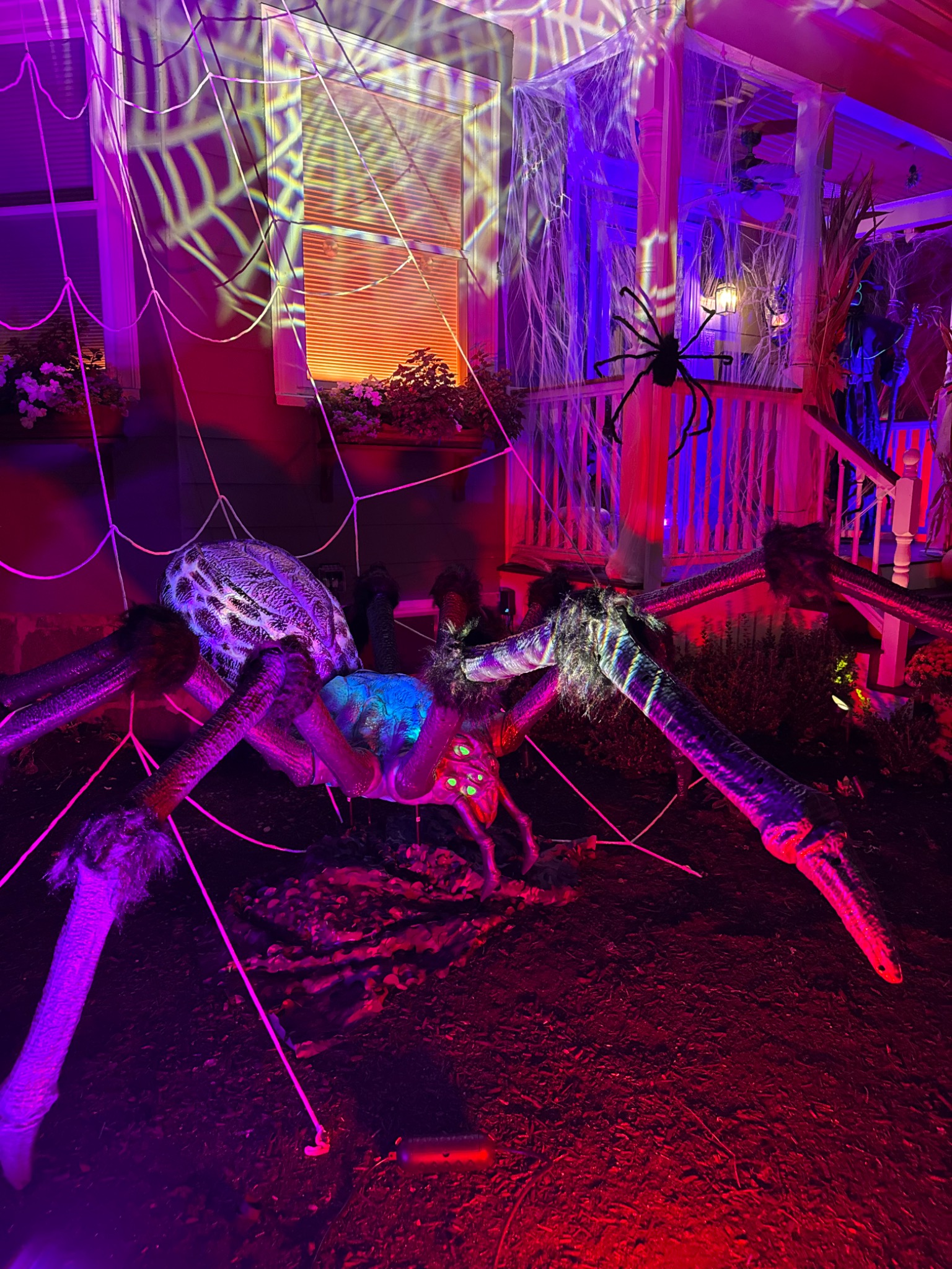 The giant spider beneath webs and colored lighting.